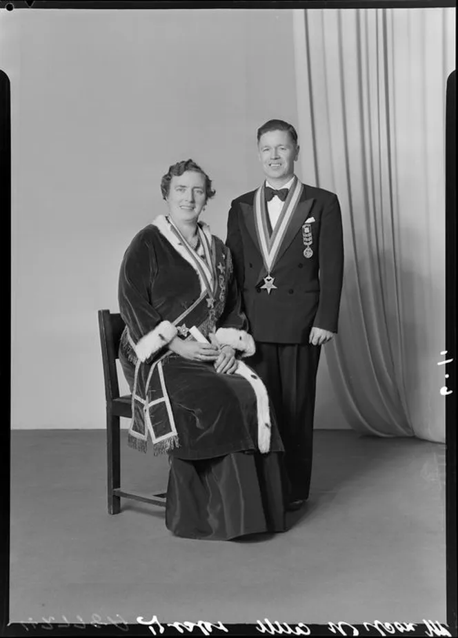 A seated woman and a standing man wearing Eastern Star regalia in a 1961 portrait by Crown Studios of Wellington; their names are not identified in the library record.
